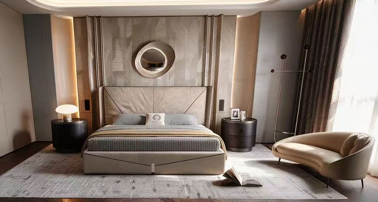Original supplied bedroom photo with an upholstered bed, circular mirror, dark bedside tables and cream lounge chair